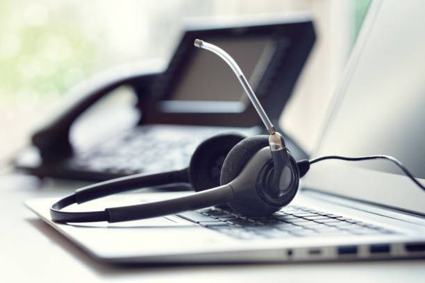 Black headset with microphone resting on a laptop keyboard in an office setting