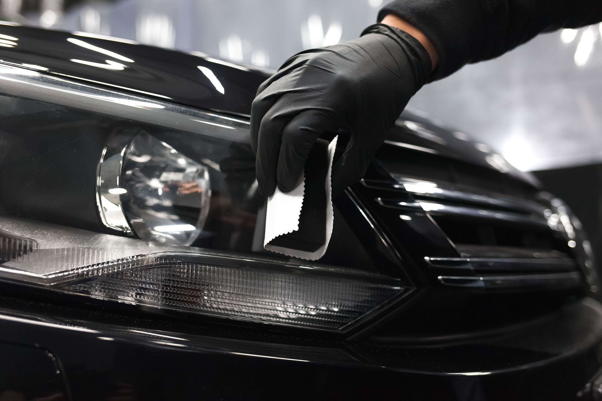 Technician applying dark tint film to a car headlight