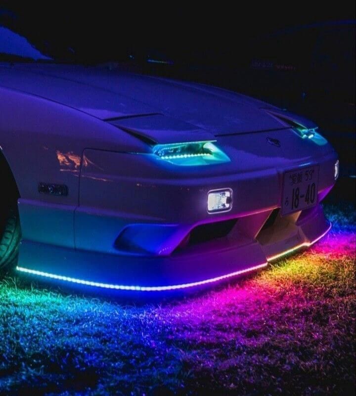 A front-angle shot of a classic sports car, resembling a Nissan 180SX, showing off multi-colors