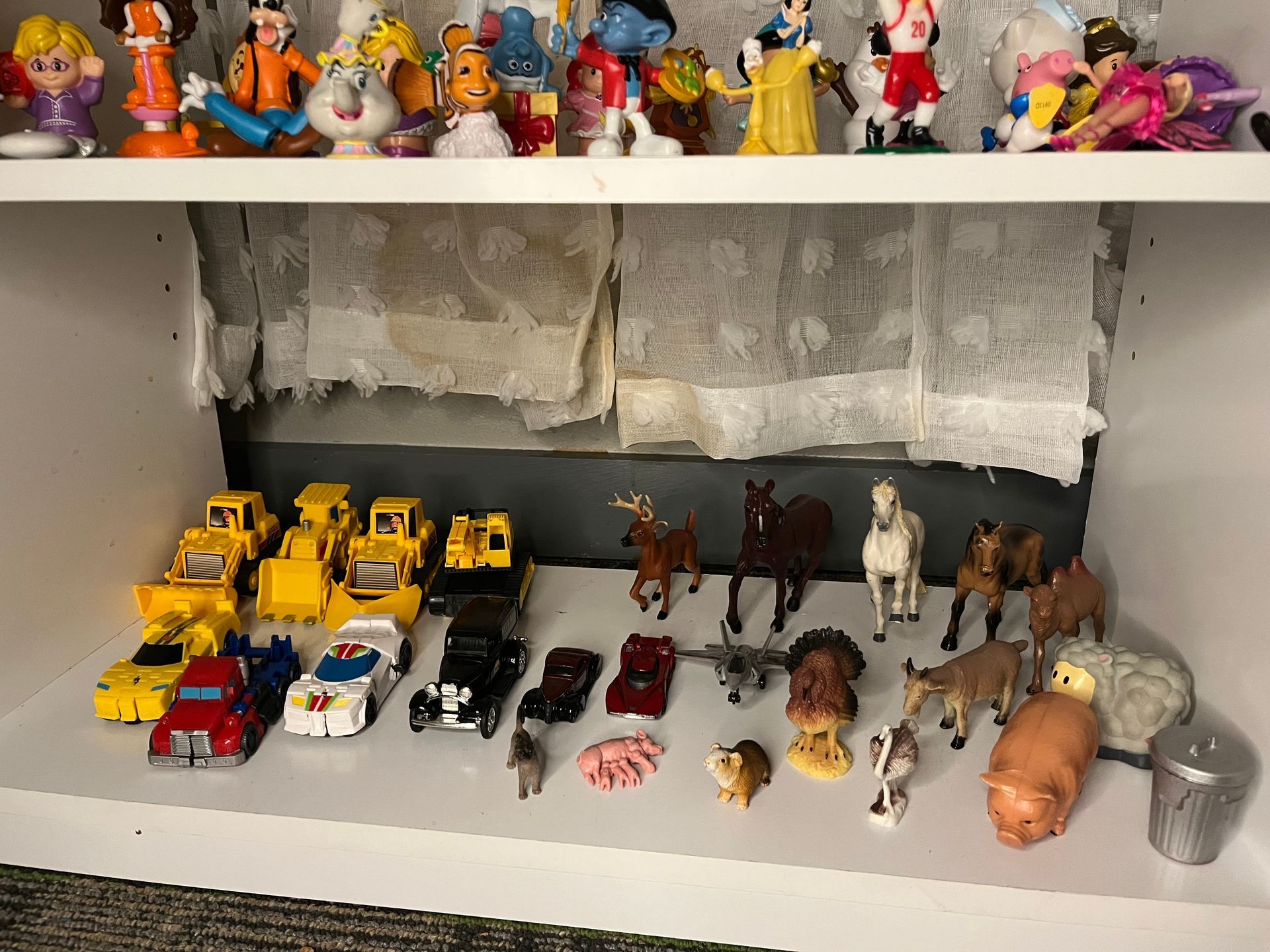 A shelf filled with lots of toy cars and animals