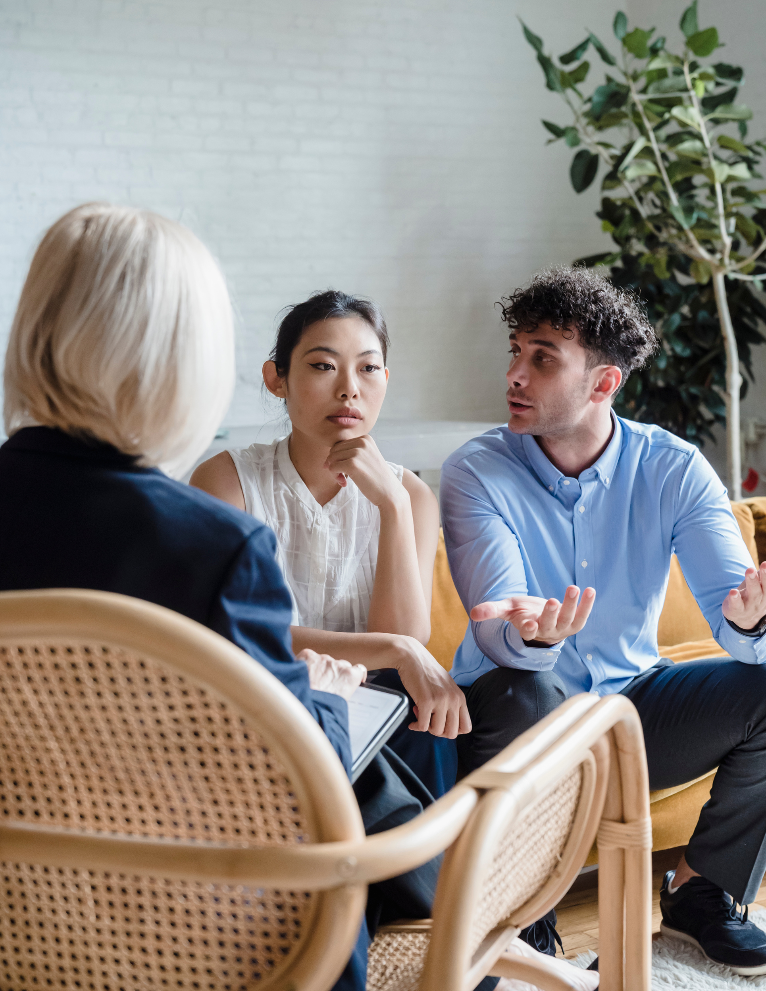 A man and a woman are sitting in chairs talking to a woman.