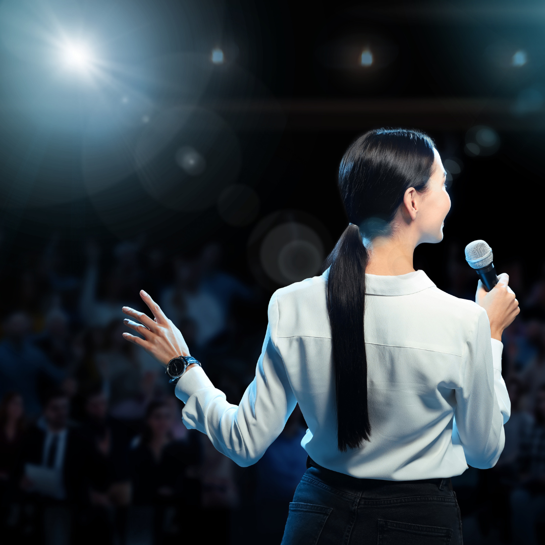 A woman is holding a microphone in front of a crowd.