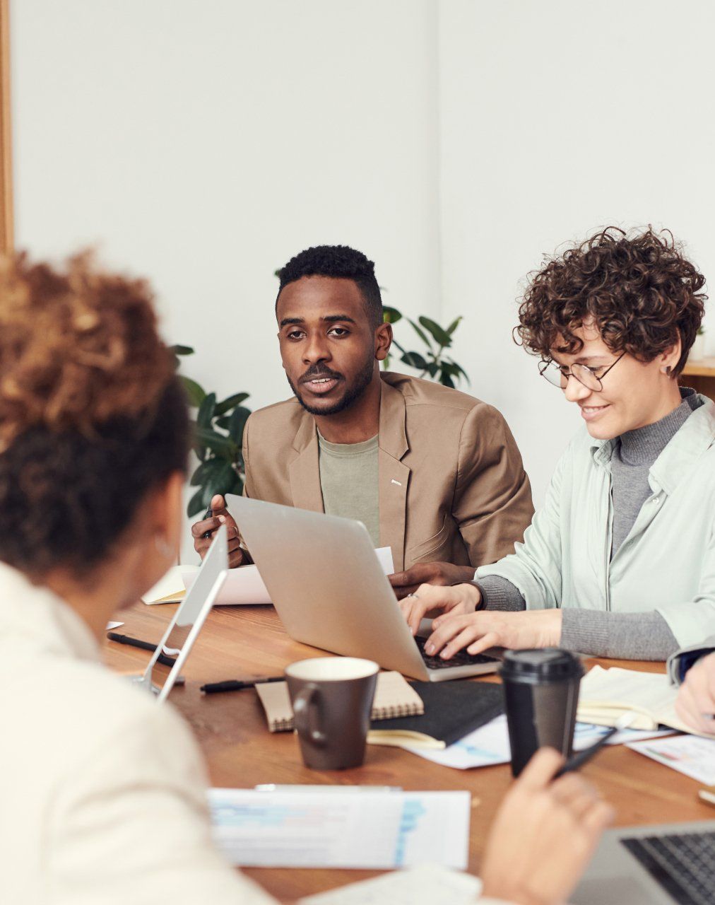 A group of people are sitting around a table with laptops.