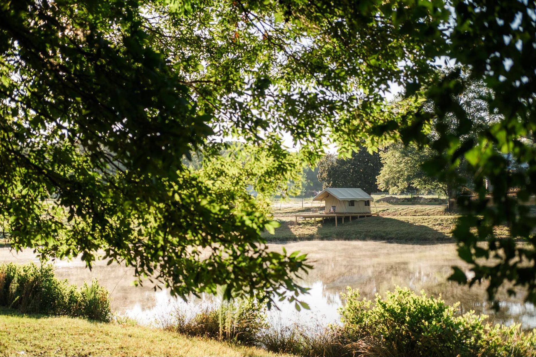 A small house is sitting on a small island in the middle of a lake surrounded by trees.