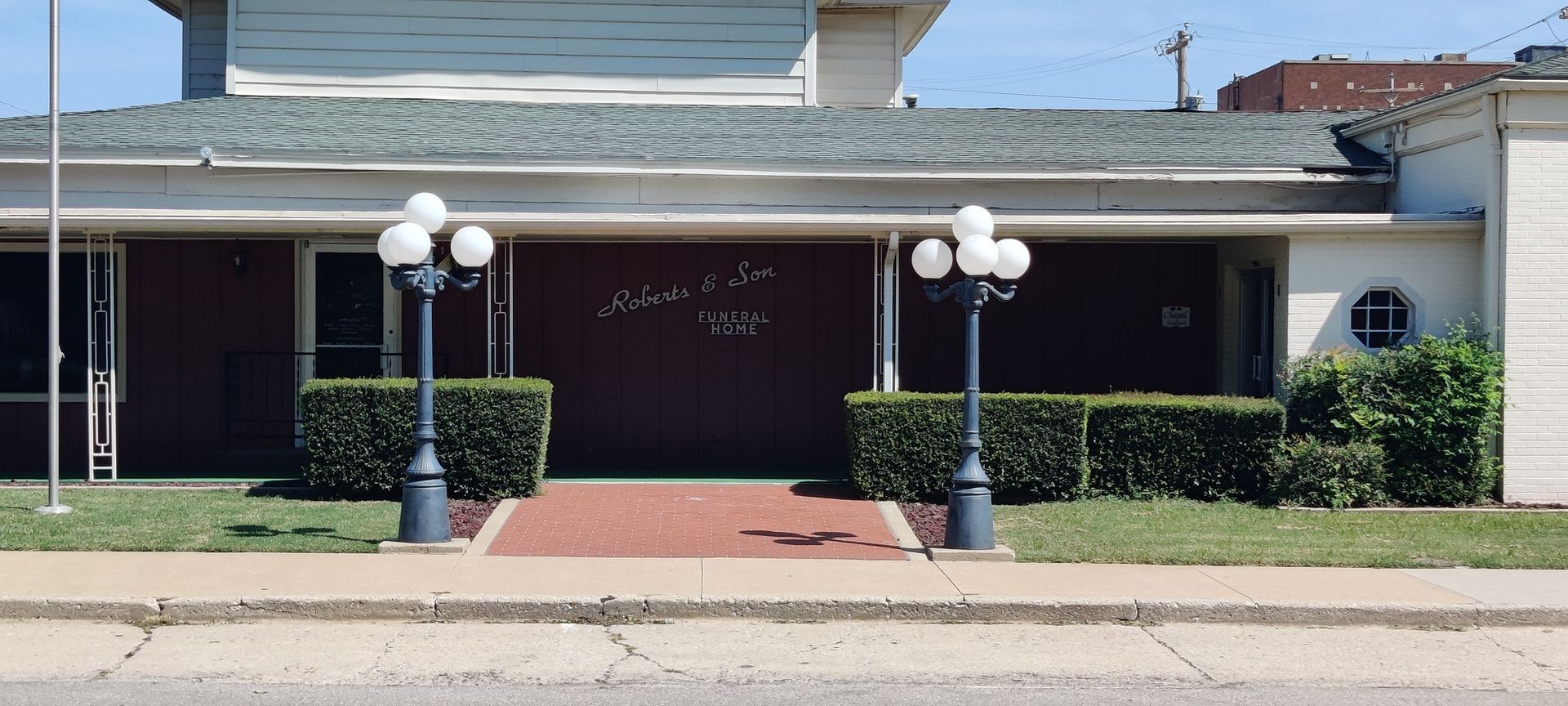 A low-slung brick building with decorative lamp posts and a brick walkway.