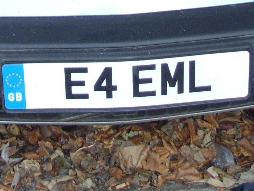 UK-style license plate reading “E4 EML” on a black car, with blue GB strip on the left.