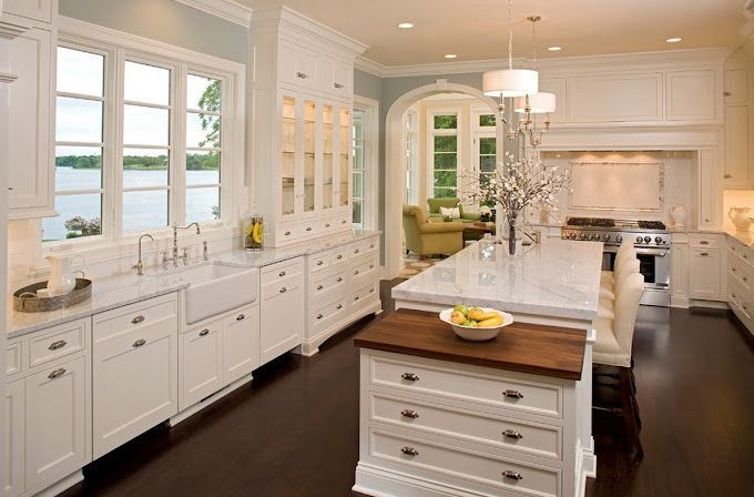 A kitchen with white cabinets and a large island in the middle