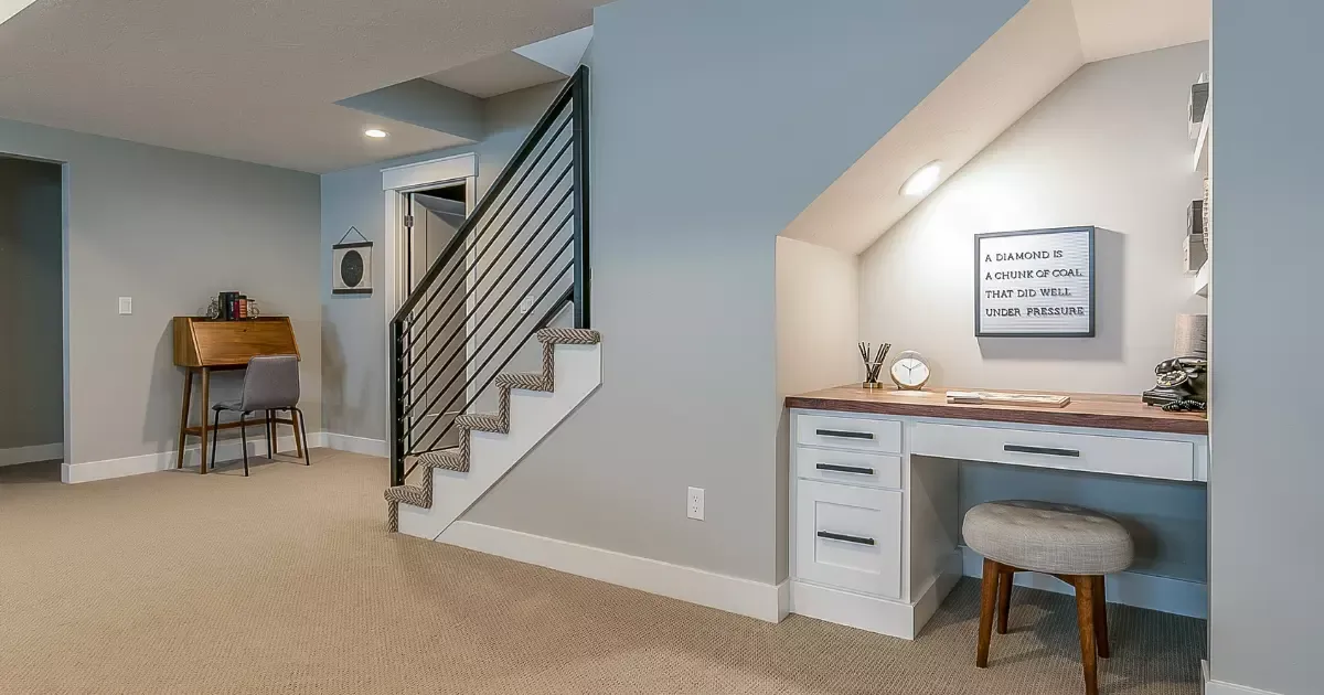 Finished basement family room with built-in desk under stairs and cozy workspace nook