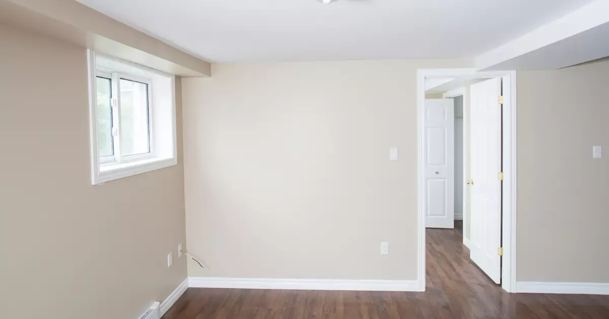 Bright basement bedroom with egress window and fresh paint after basement remodeling