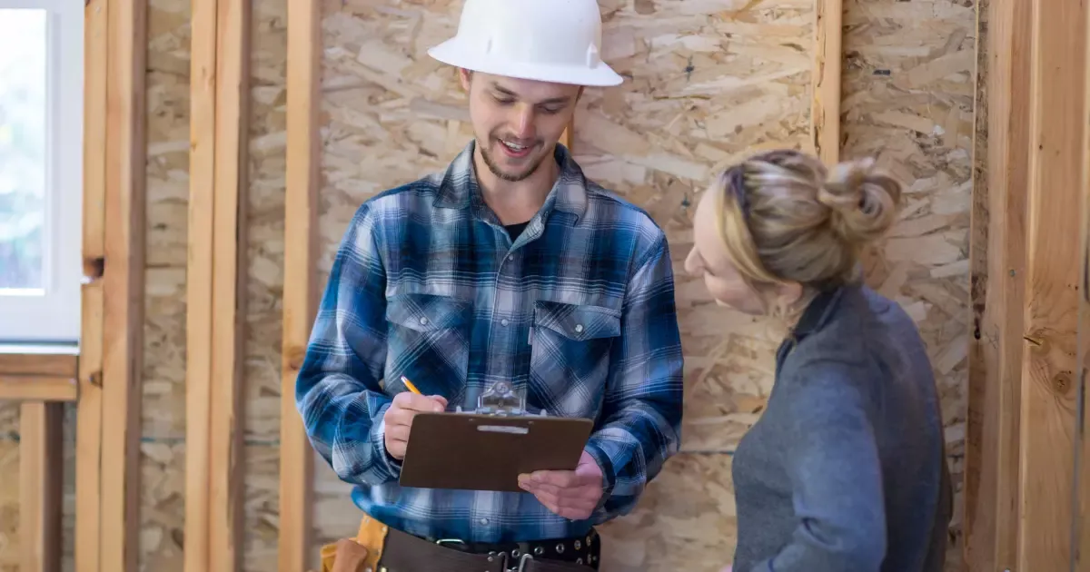 Homeowner reviewing plans with contractor at framed construction site, remodeler near me consultation