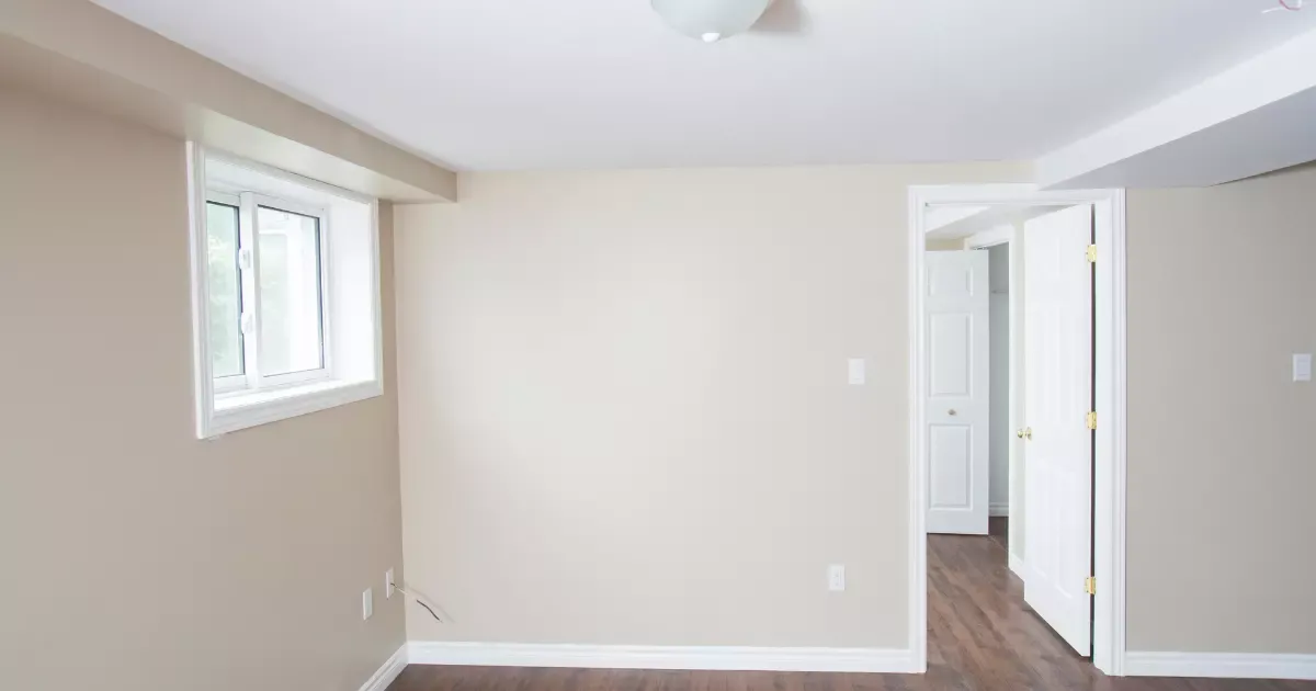 Finished basement room with window and neutral walls, ideal for soundproofing a basement to reduce outside noise