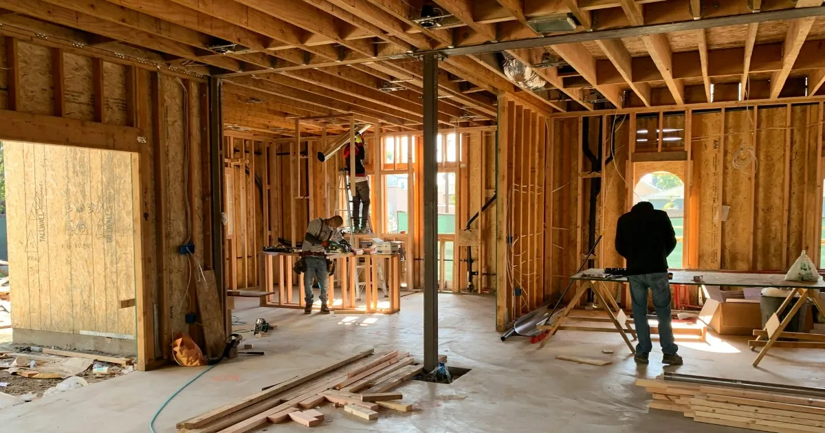 Interior framing stage of custom home building with contractors working on walls and structural layout