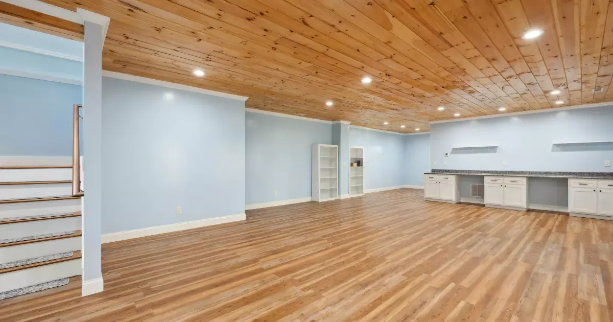 Spacious finished basement with wood ceiling, vinyl flooring, and built-in cabinets for quality basement finishing