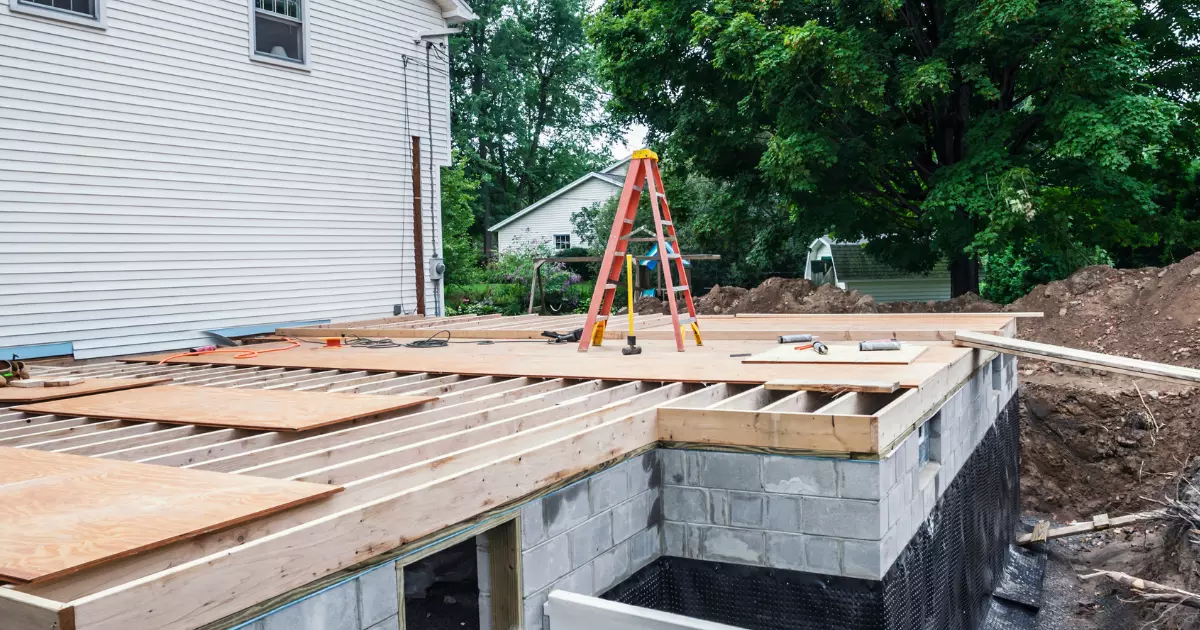 Wood framing and foundation work underway for home construction extension project beside existing house