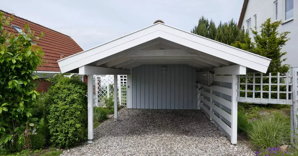 White gable-style custom carport with gravel base in residential yard