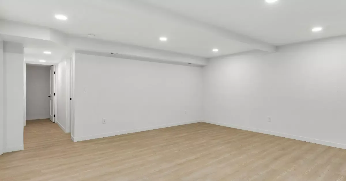 Bright modern basement with light vinyl basement flooring and recessed ceiling lights