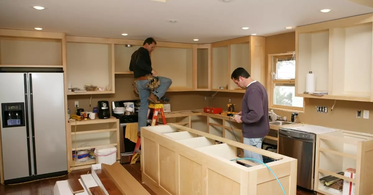 Two contractors installing kitchen cabinets and island during a home remodeling project