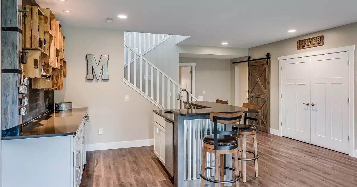 Modern basement finishing with custom wet bar, wood shelving, sliding barn door, and staircase access
