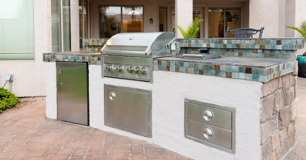 Modern outdoor kitchen with built-in grill and tiled counter installed during basement remodeling project