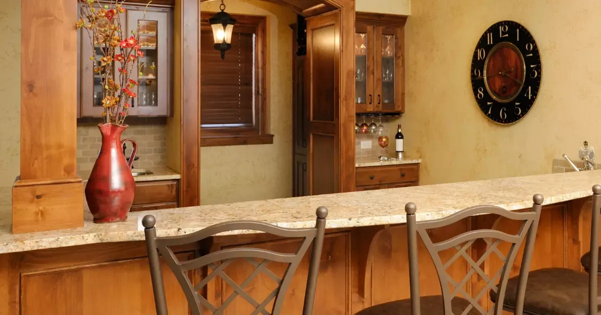 Basement remodeling featuring custom wood bar, granite countertop, built-in cabinets, and decorative accents