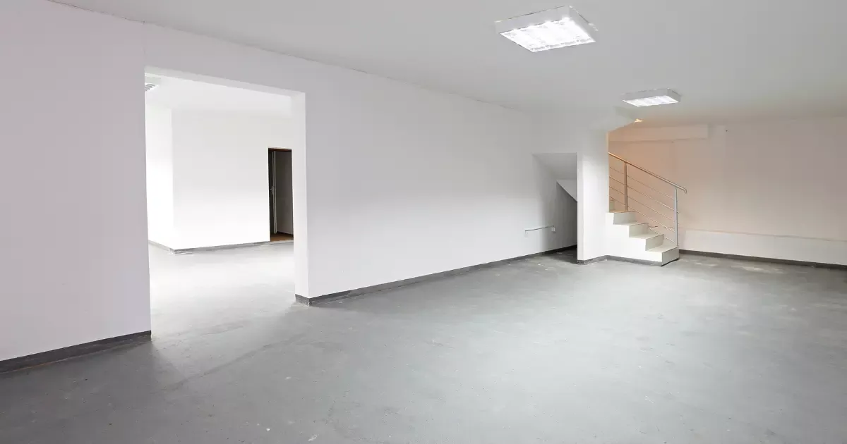 Clean open basement with smooth polished concrete basement flooring and staircase access