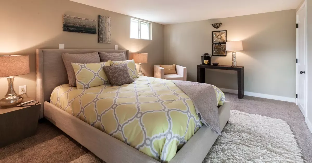 Cozy basement bedroom with plush carpet and soft furnishings, example of soundproofing a basement for quieter living space