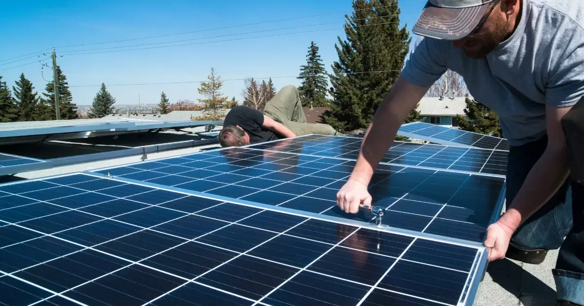 Two workers fastening solar panels in place during residential solar panel installation