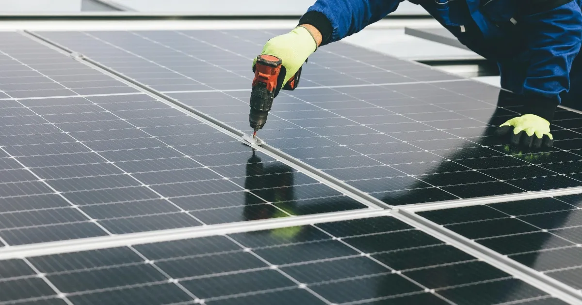 Technician installing rooftop solar panels with a drill as part of a residential solar lease agreement