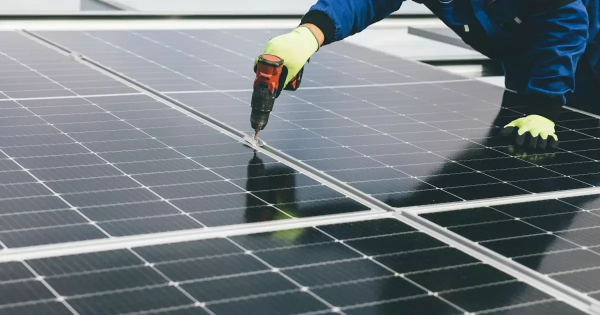 Technician using drill for solar panel maintenance