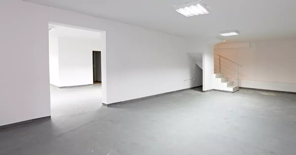 Unfinished open basement space with concrete floors and staircase, ready for professional basement finishing