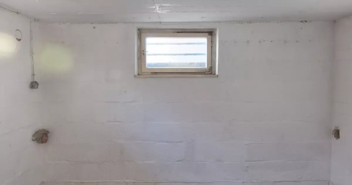 Unfinished basement wall with small window and exposed outlets, ready for basement remodeling transformation