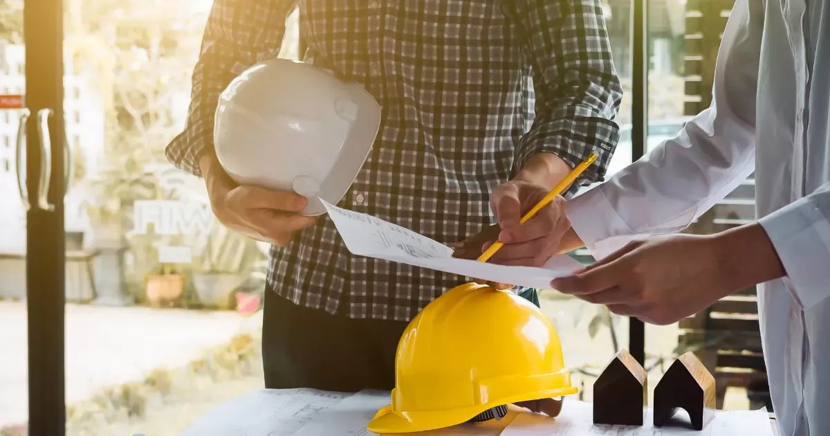 A group of people holding a pencil and a paper with white hard hat and yellow hard hat