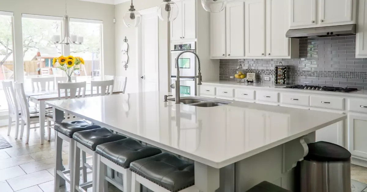 A kitchen with white cabinets and a large island in the middle