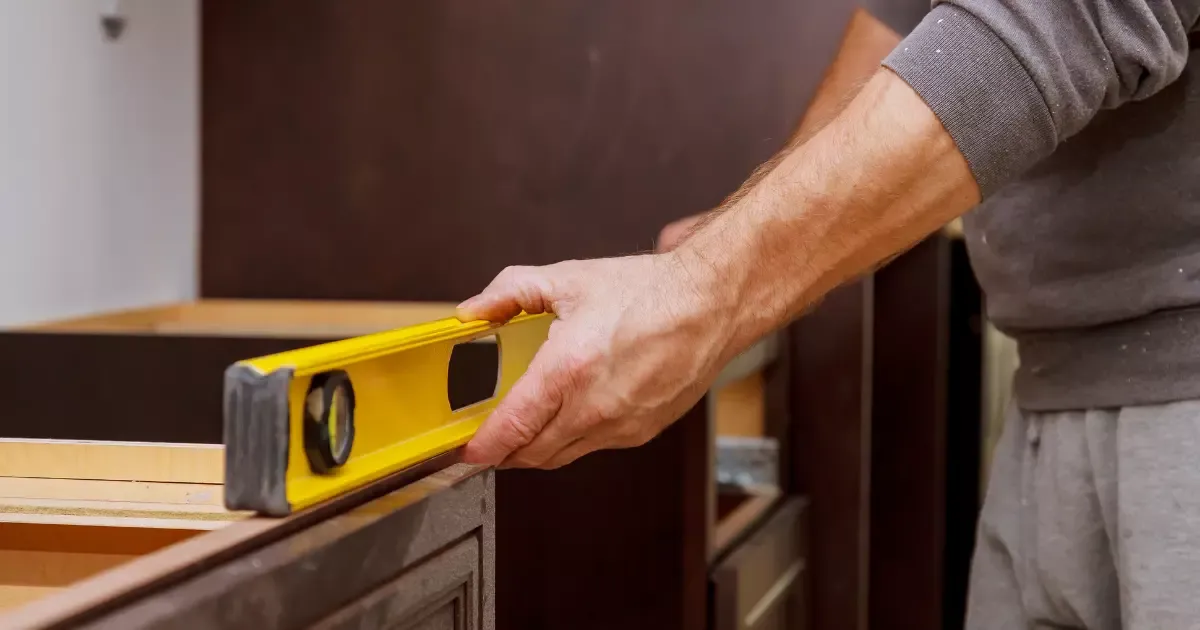 Custom home builder using level to align cabinetry during interior home construction project