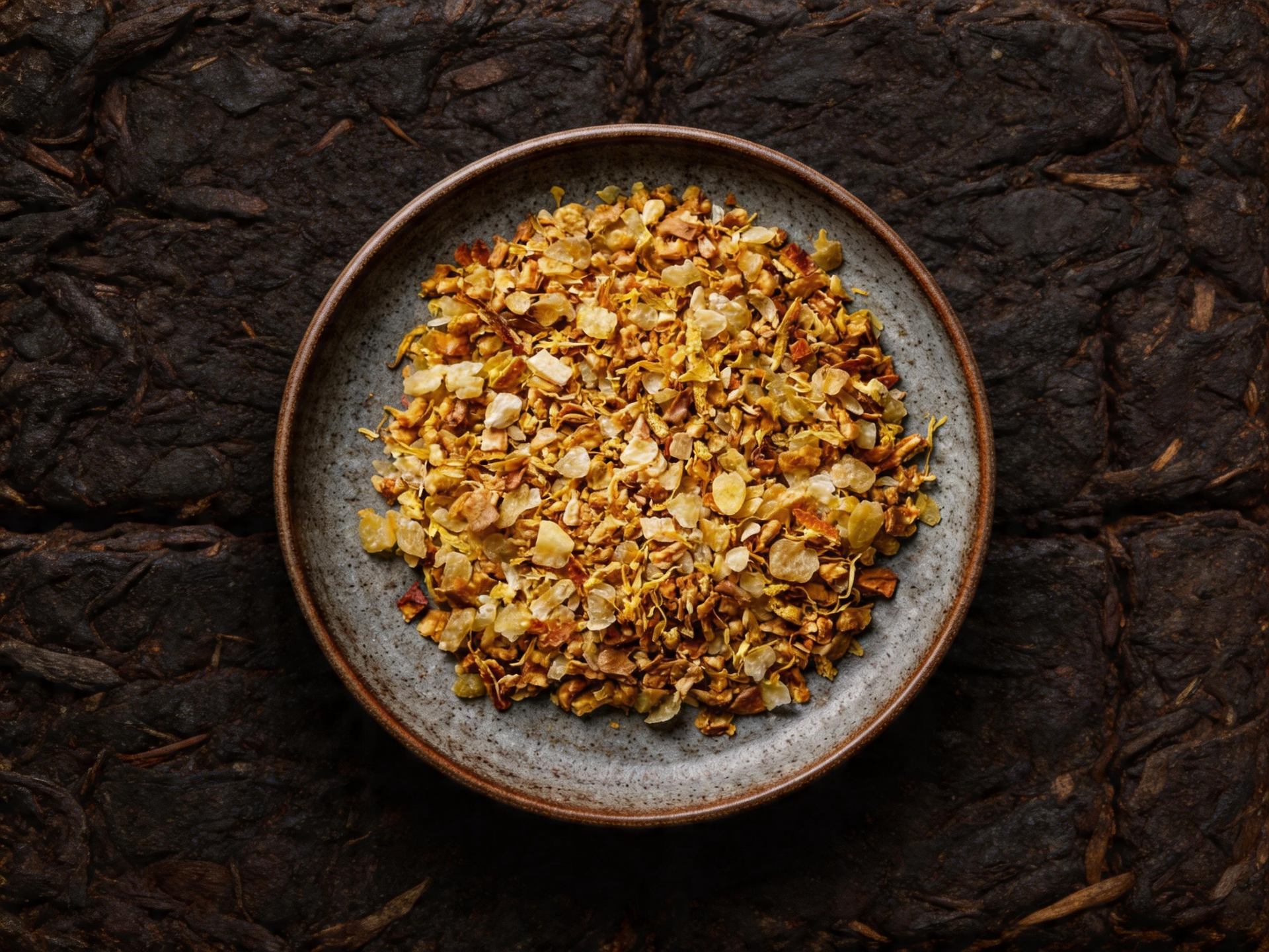 Bowl of crushed red pepper flakes on a dark stone surface
