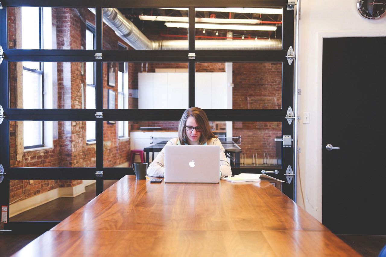 A woman is sitting at a table using a laptop computer.