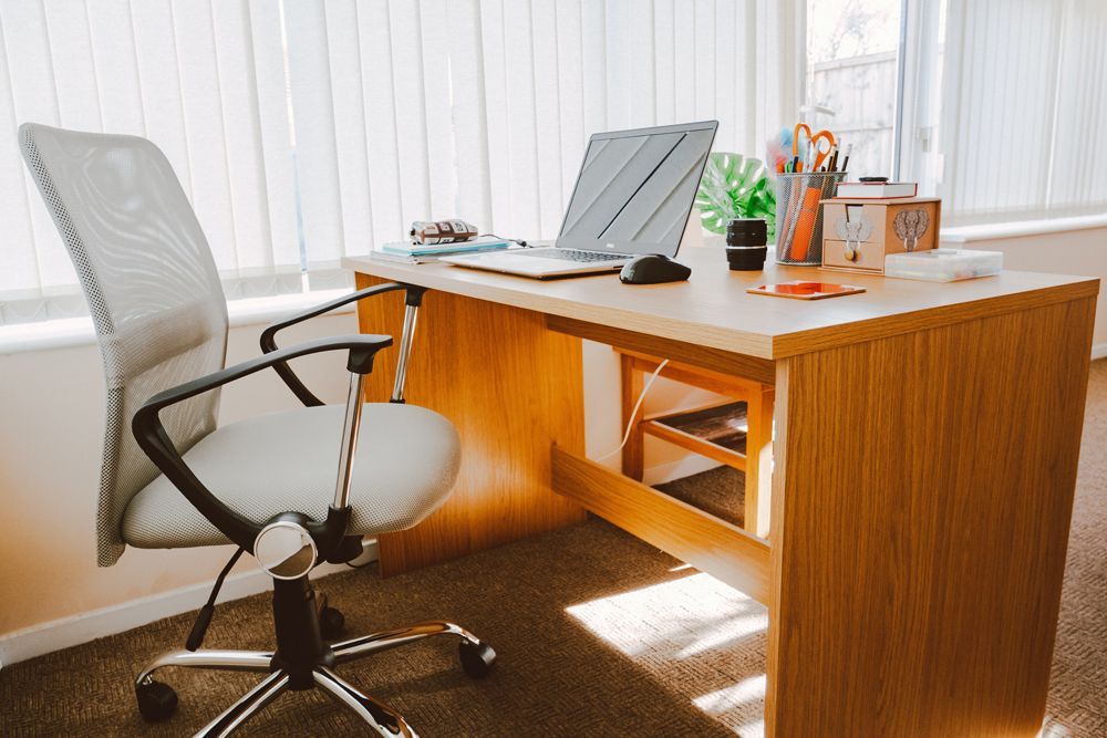 A wooden desk with a chair and a laptop on it.