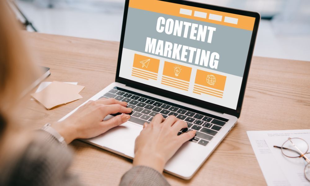 A person is typing on a laptop computer with the word content marketing on the screen.