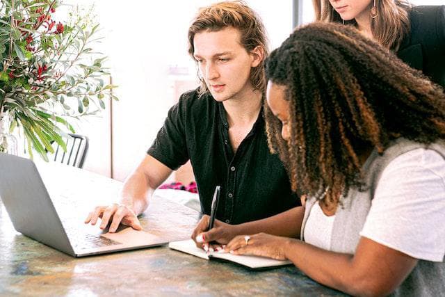 Hire a Digital Marketing Agency Right Now A group of people are sitting at a table looking at a laptop computer.
