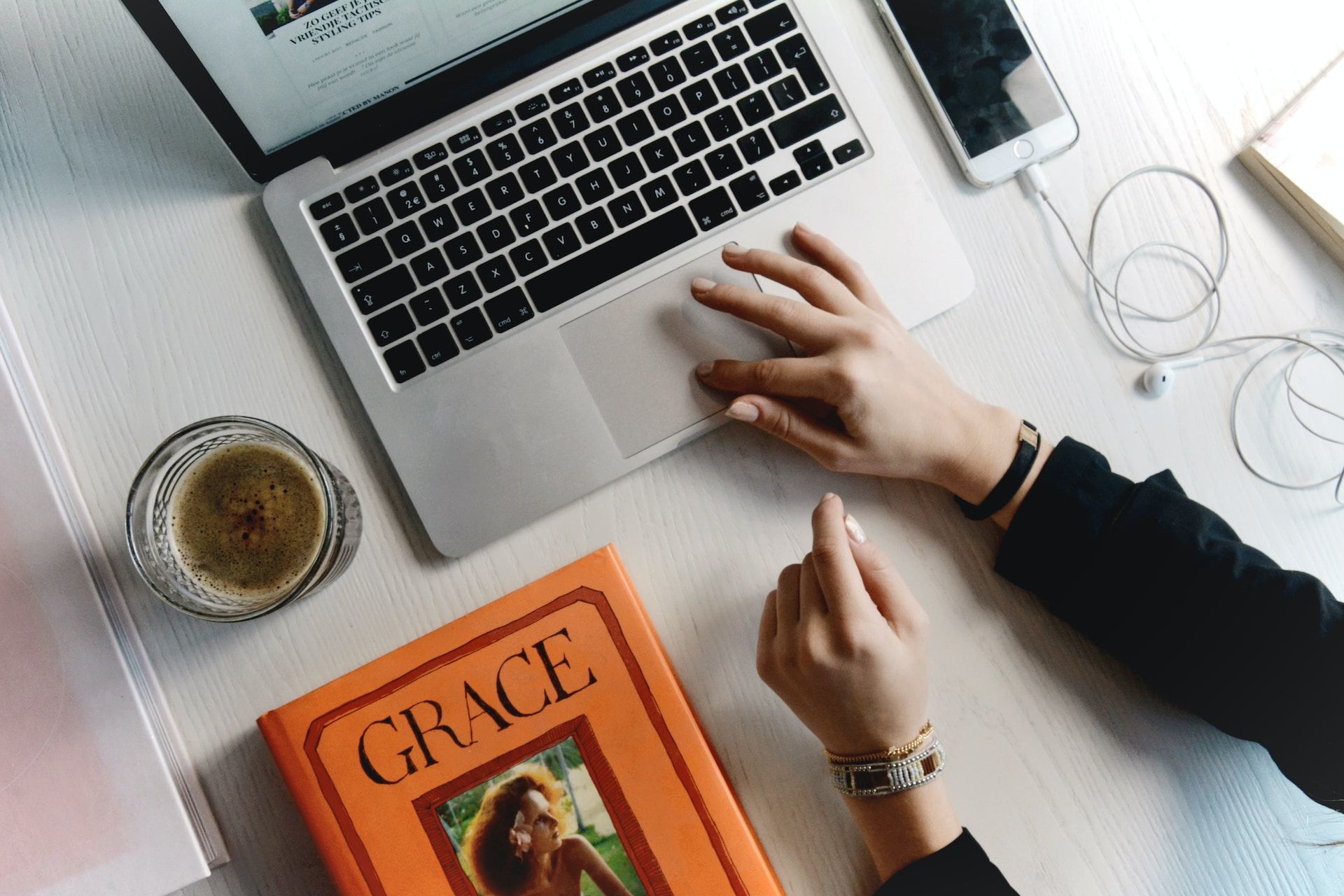 A person is typing on a laptop next to a book titled grace.