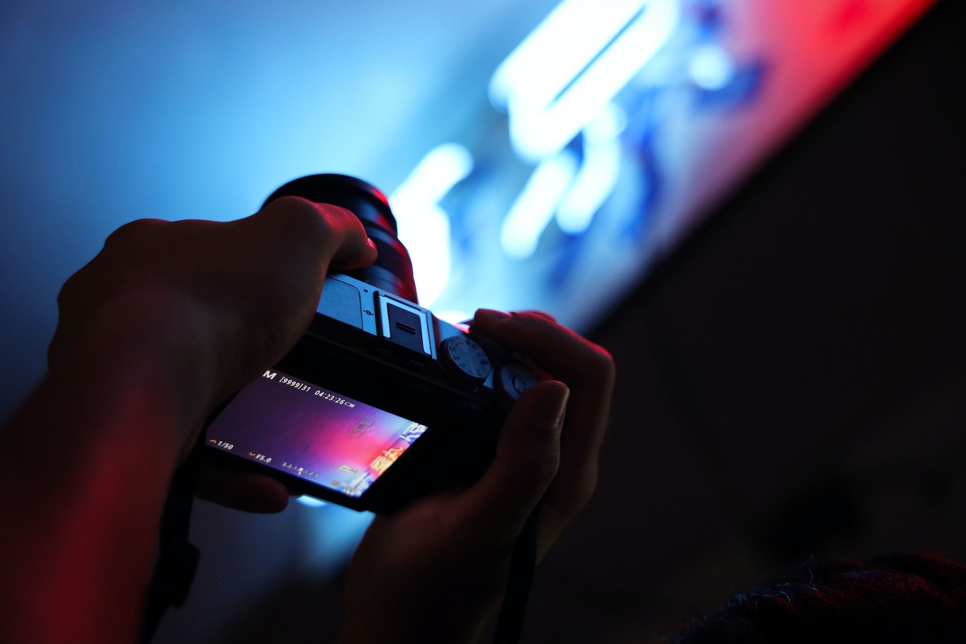 A person is taking a picture of a neon sign with a camera
