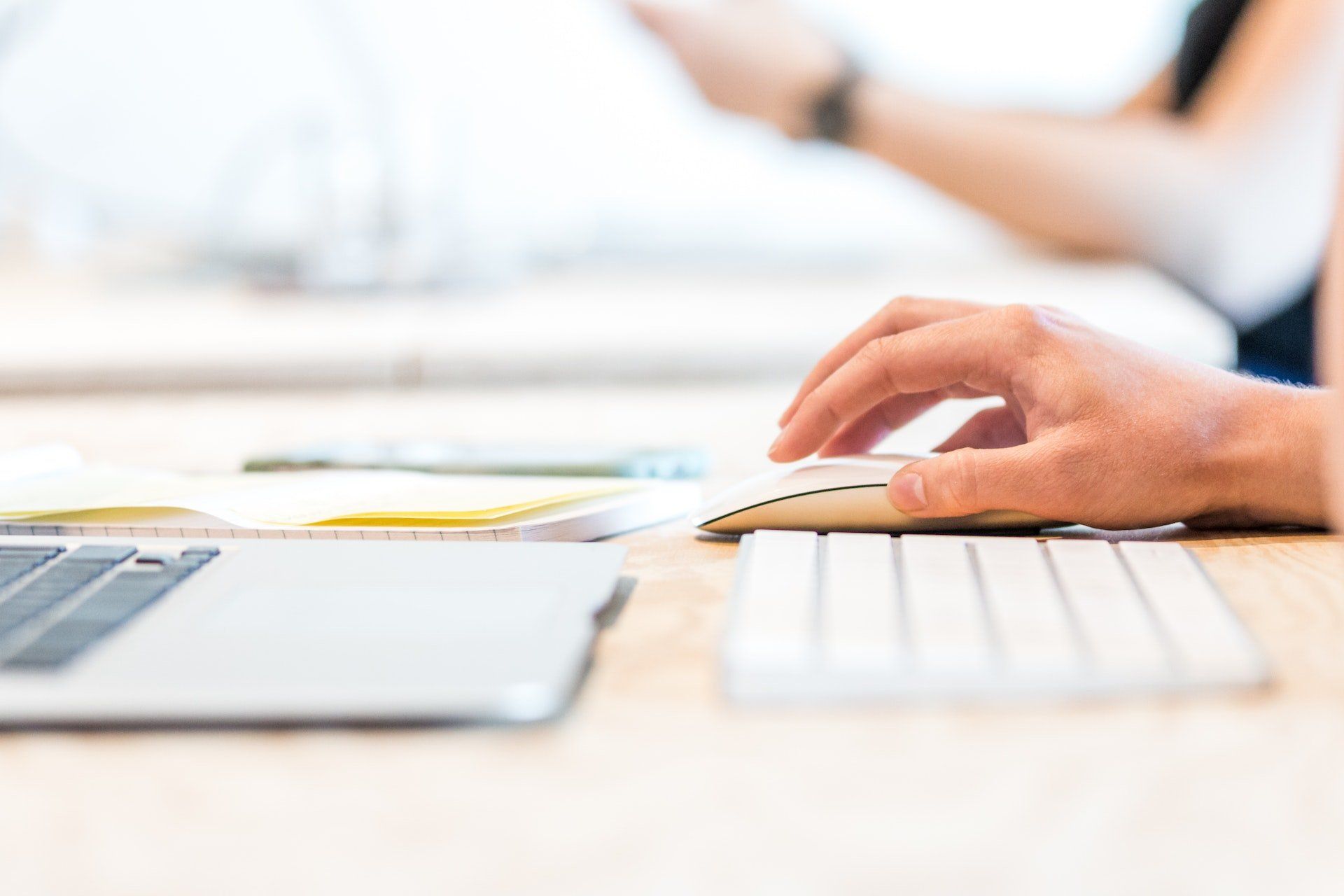 A person is typing on a computer keyboard with a mouse.