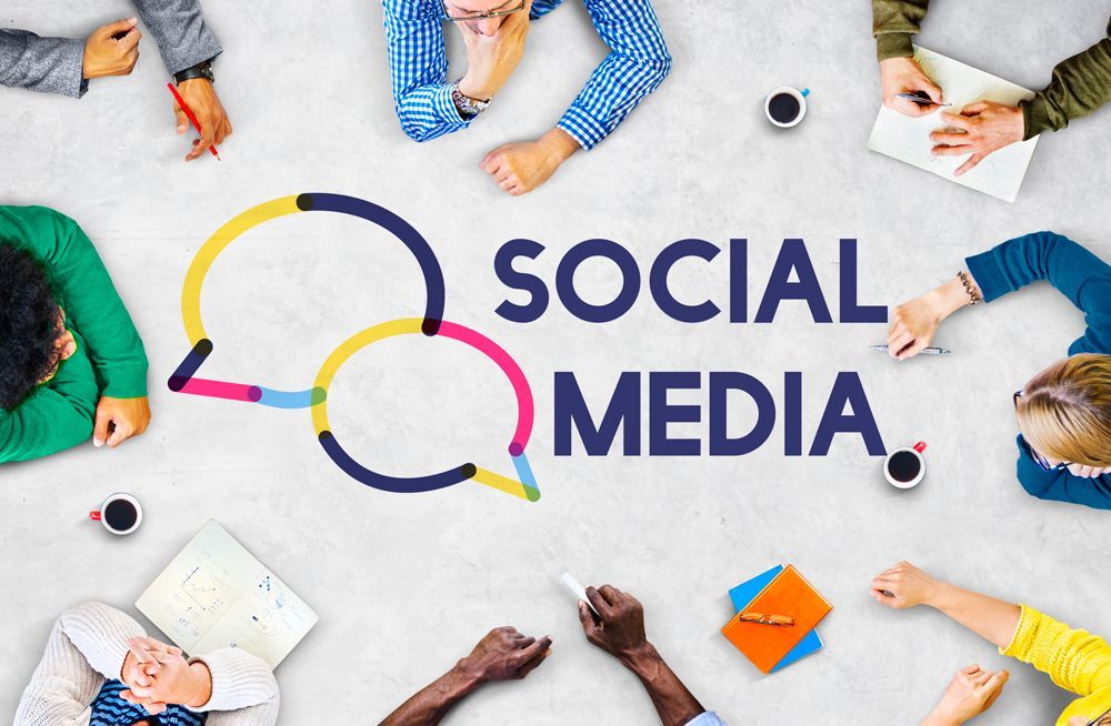 A group of people are laying around a table with the words social media written on it.
