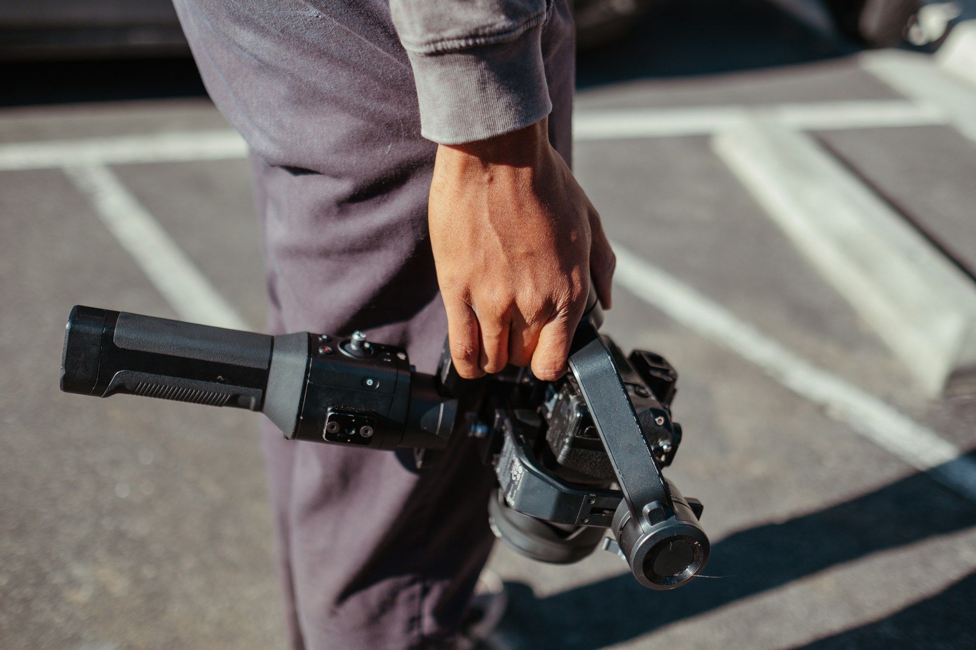 A person is holding a camera in their hand in a parking lot.