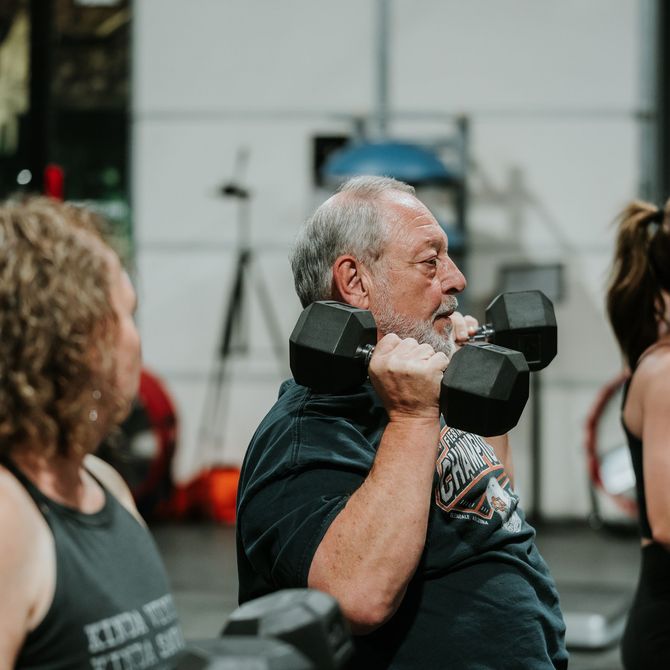 Man lifting dumbbells in a gym, mid-exercise with focused expression