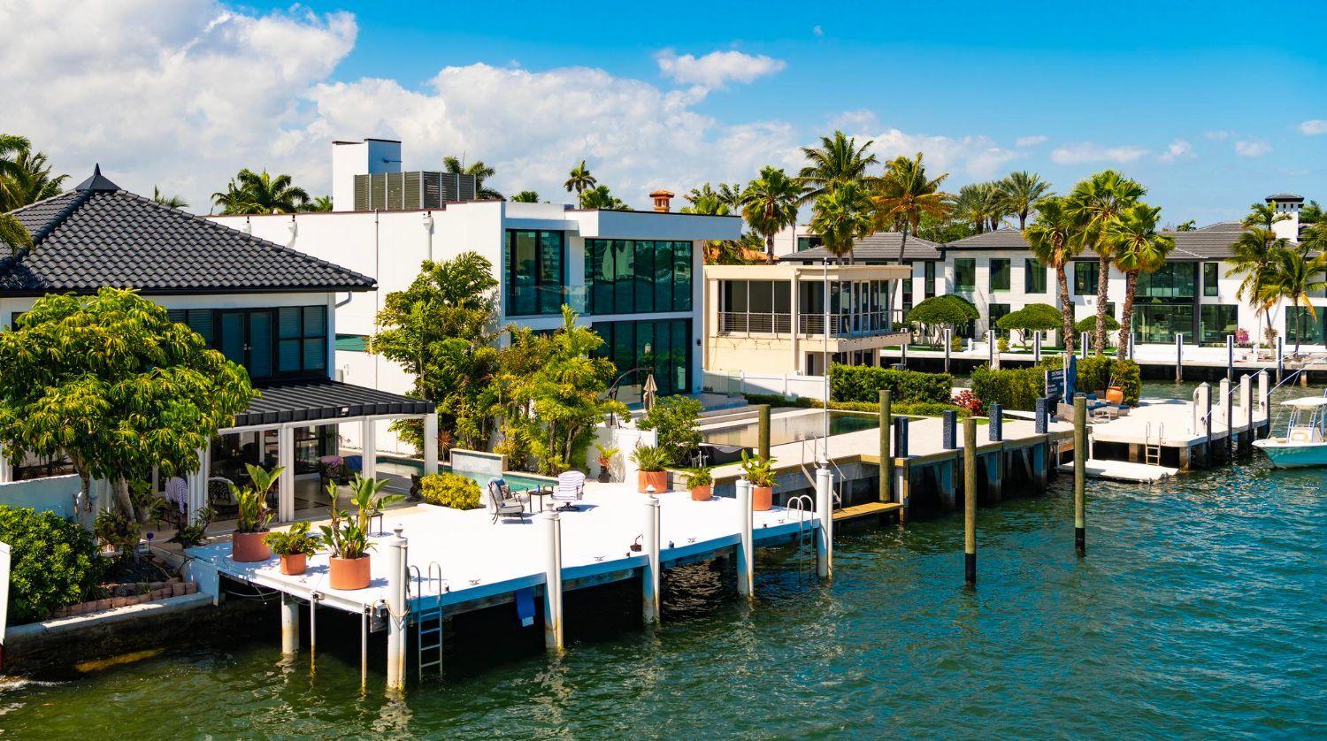 Waterfront villas with palm trees and docks along a bright tropical bay