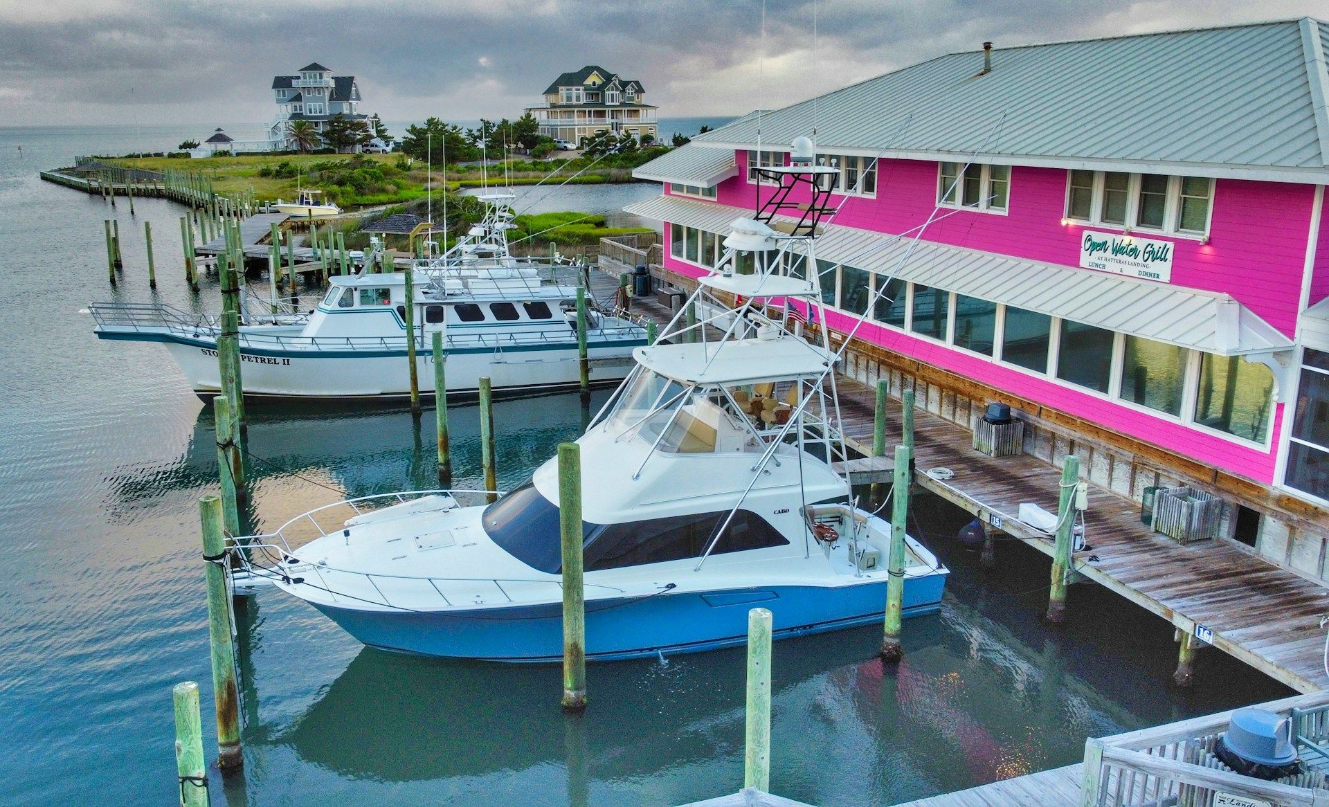 Waterfront marina with pink building and several yachts docked beside it