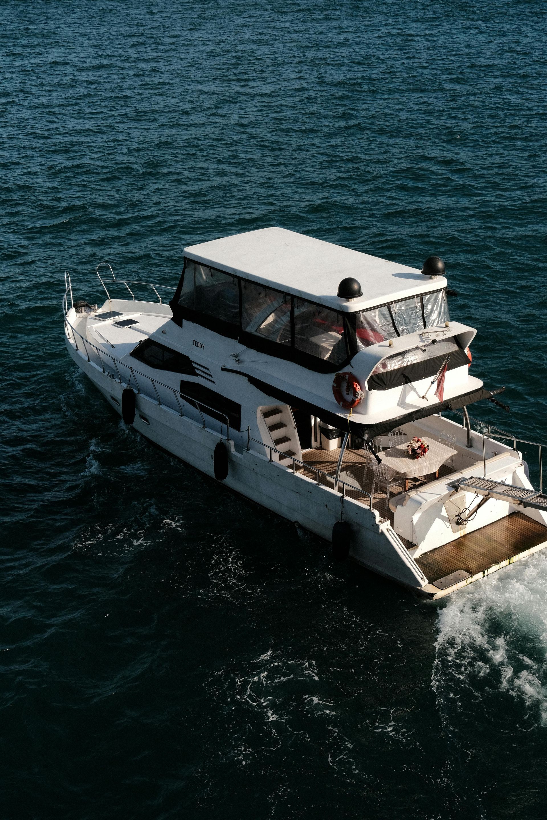 White motor yacht cruising on dark blue water, viewed from above