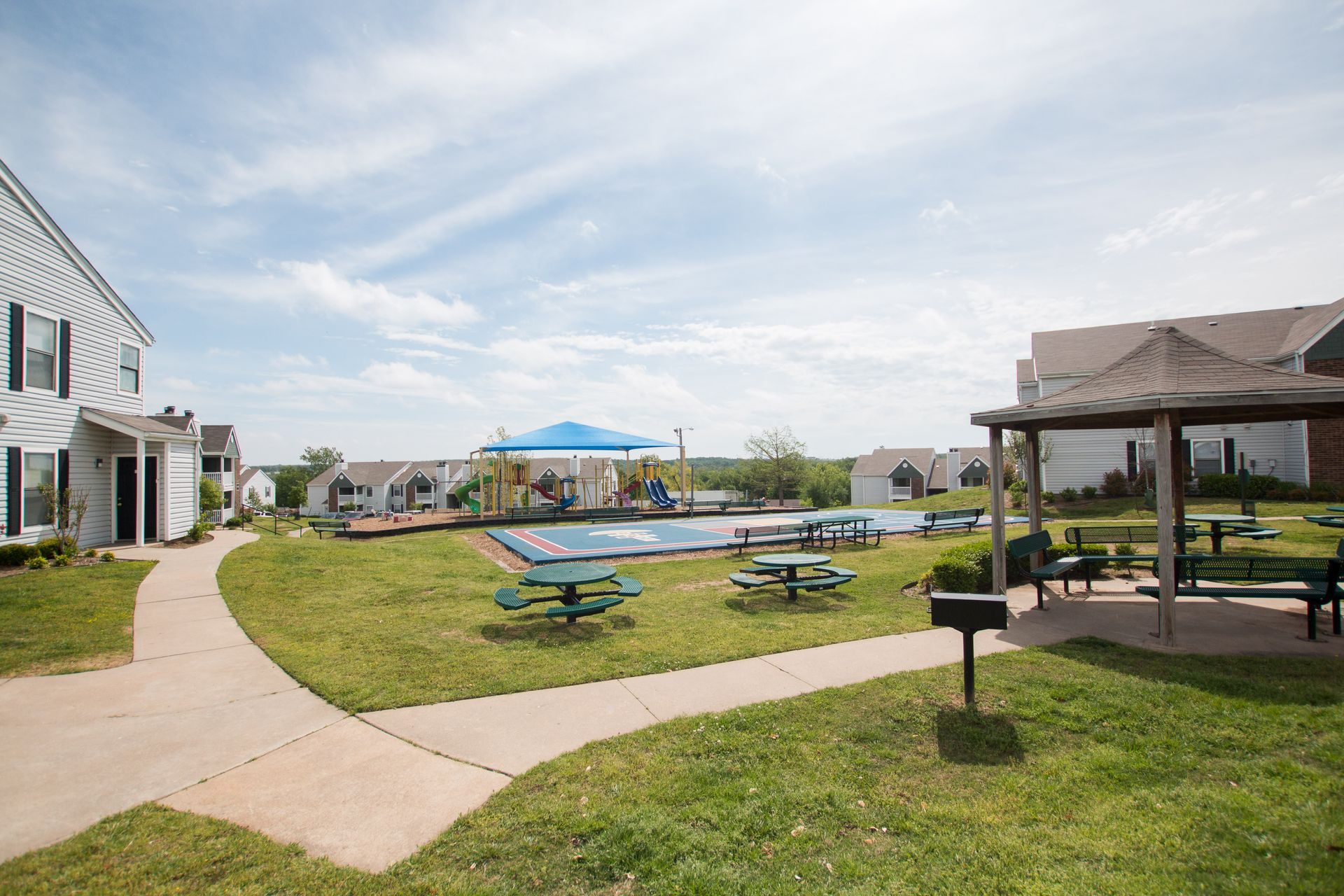 A picnic area with tables and chairs in front of a house.