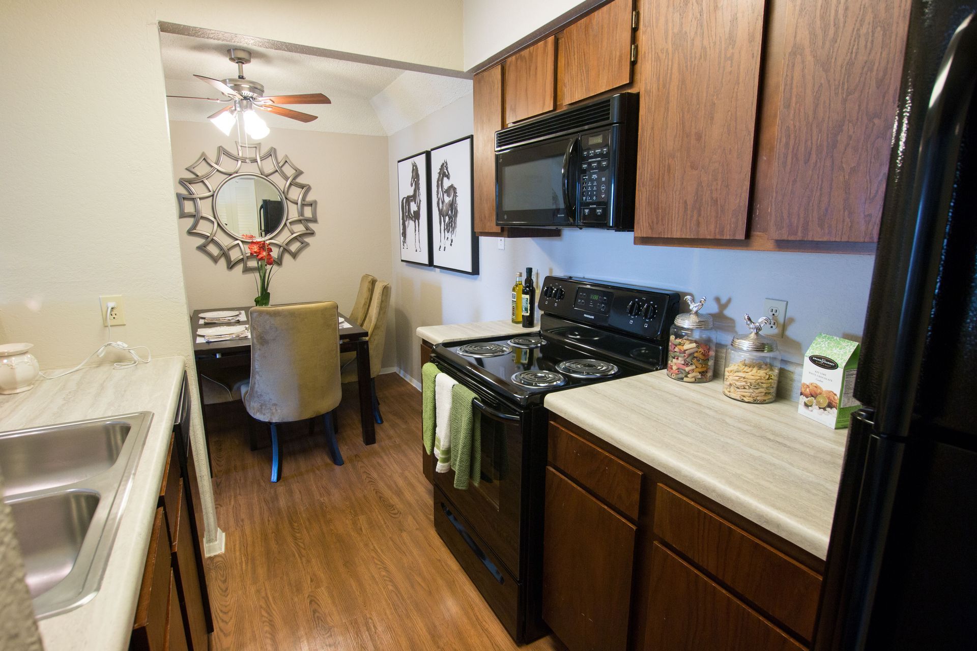 A kitchen with a stove , refrigerator , microwave and sink.